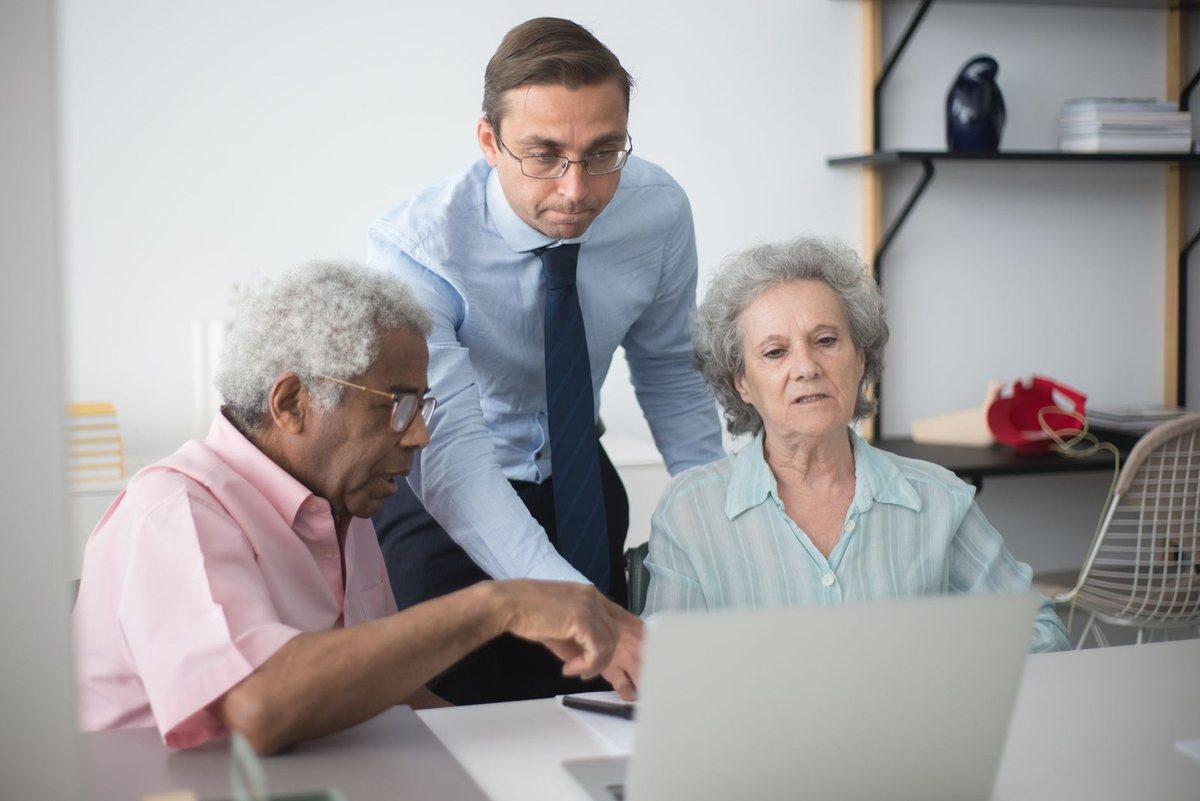 Groupe mixte consultatif autour d'un ordinateur portable dans un environnement de bureau