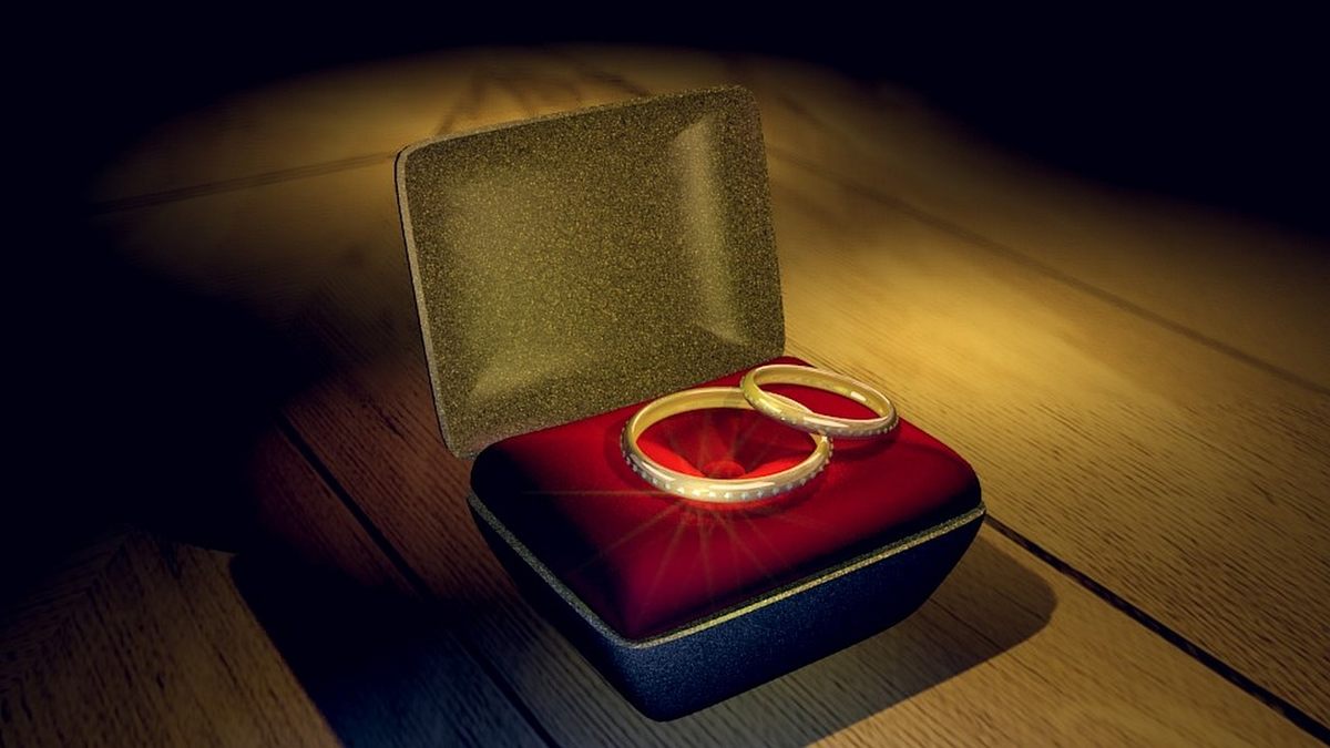 Deux bagues d'or reposent sur un coussin rouge dans une boîte à bijoux