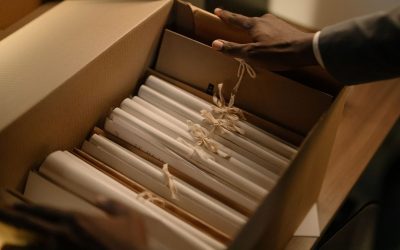 Mains ouvrant un carton avec des documents reliés par ficelle
