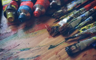 Tubes de peinture et pinceaux sur une table en bois tachée de couleurs