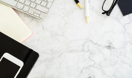 Clavier, notes, téléphone, ciseaux et stylos sur une surface marbrée