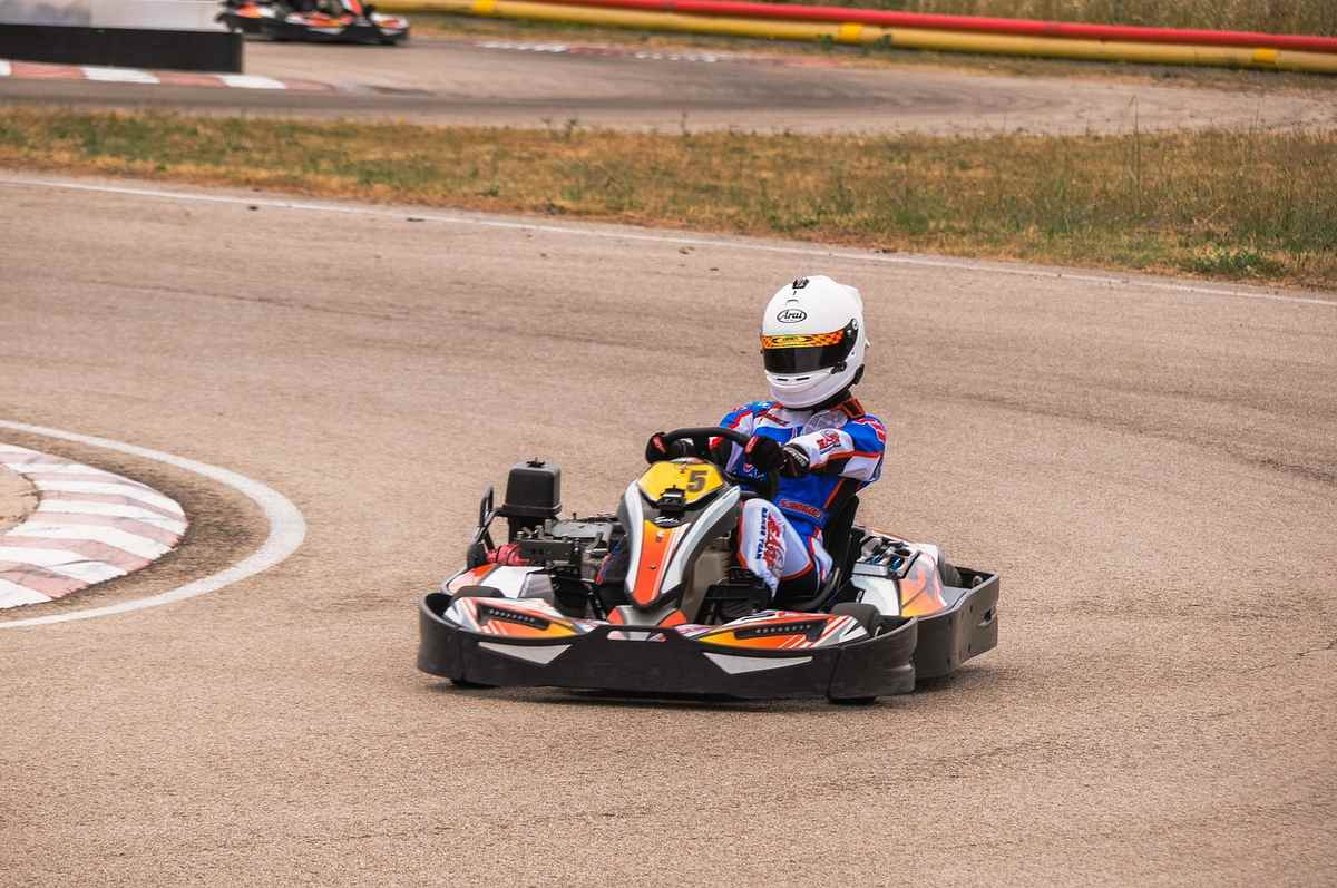 Un pilote en combinaison bleue et casque blanc conduit un kart de course