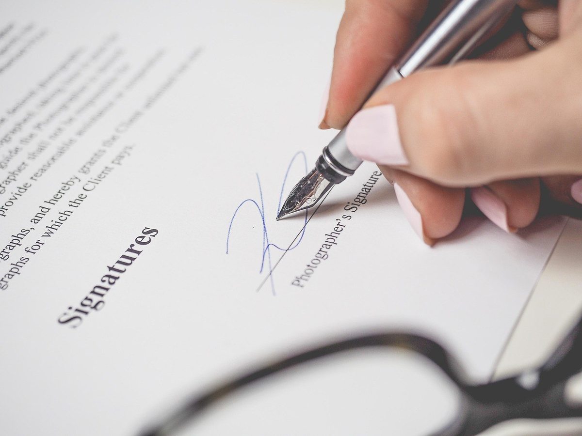 Signature manuscrite sur un document avec lunettes de lecture Signature manuscrite sur un document avec lunettes de lecture