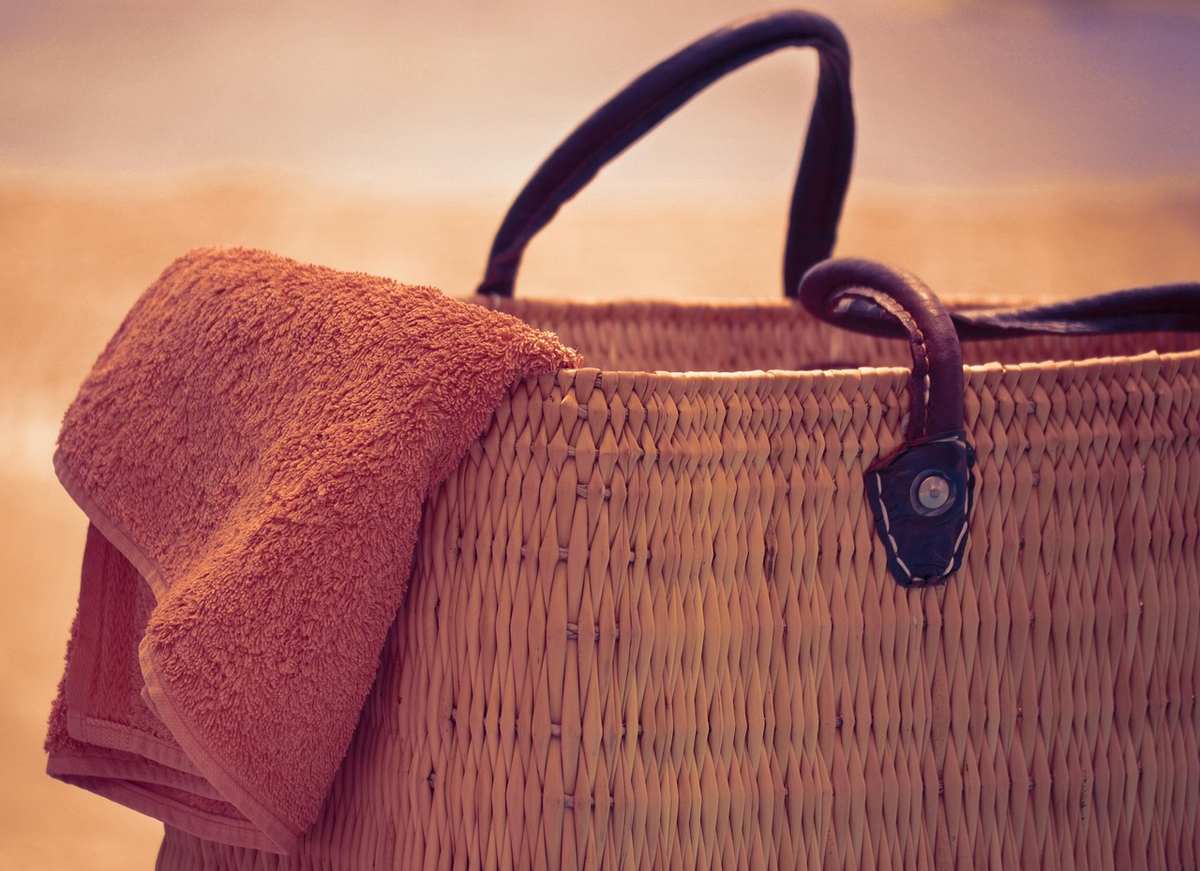 Un sac en osier avec une serviette posée sur une plage ensoleillée Un sac en osier avec une serviette posée sur une plage ensoleillée