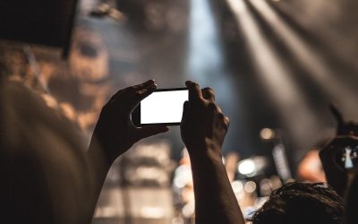 Personne filmant une scène urbaine avec son smartphone lors d'un événement