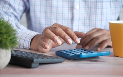 Personnes mains au clavier et à la calculatrice sur un bureau avec tasse et plante