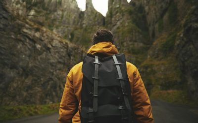 Un randonneur marche sur une route étroite entre des falaises escarpées