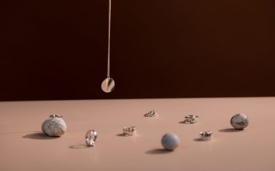 Anneaux et boules métalliques reposent sur une surface claire, un pendentif pend