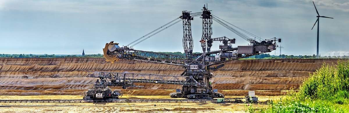 Excavateur sur une digue avec une grue et un vent éolien en arrière-plan Excavateur sur une digue avec une grue et un vent éolien en arrière-plan